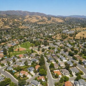 Aerial view of a sunny California neighborhood with homes, parks, and hills